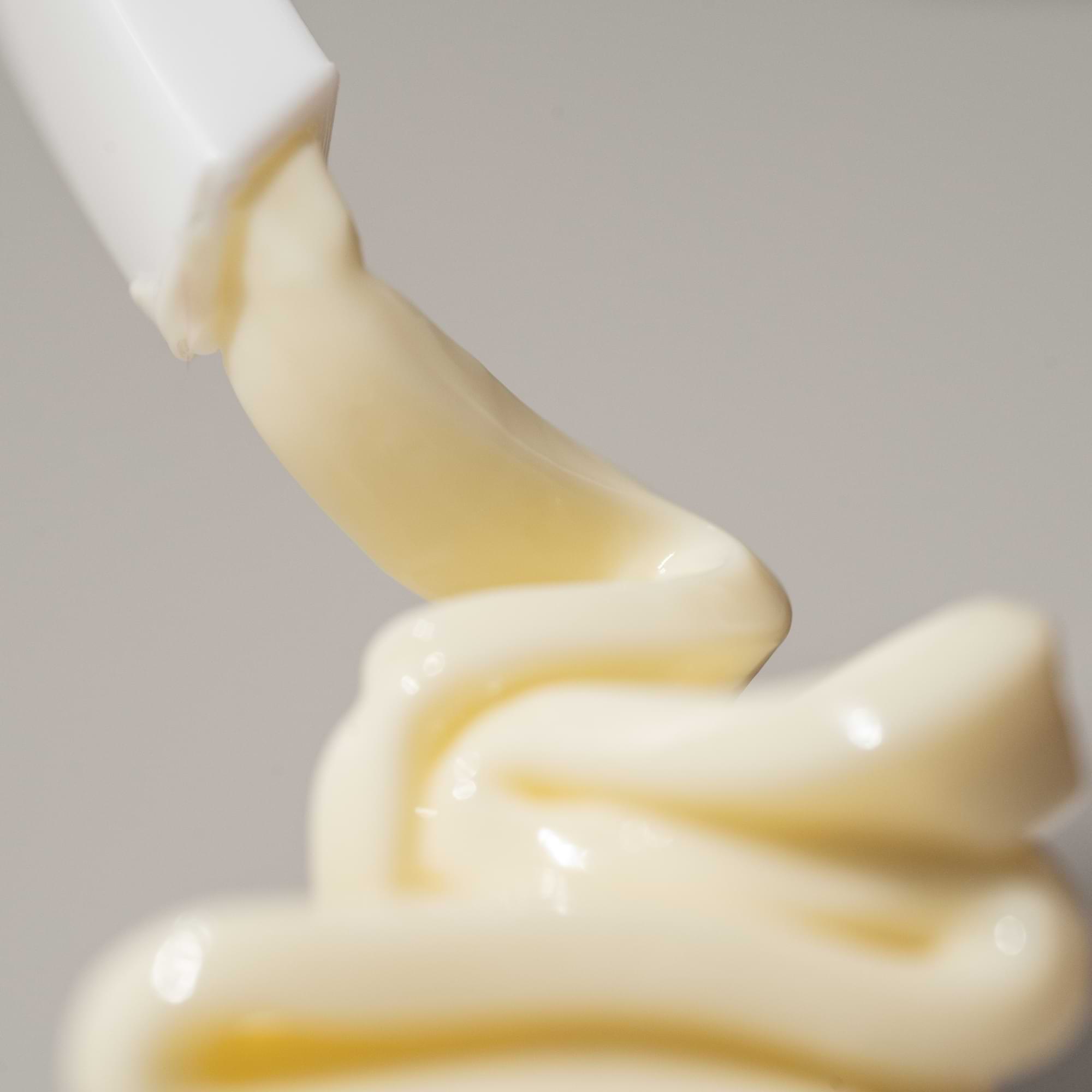 Close-up of Nokori Bio Active Cream being dispensed from a white pump, showing the creamy yellow texture