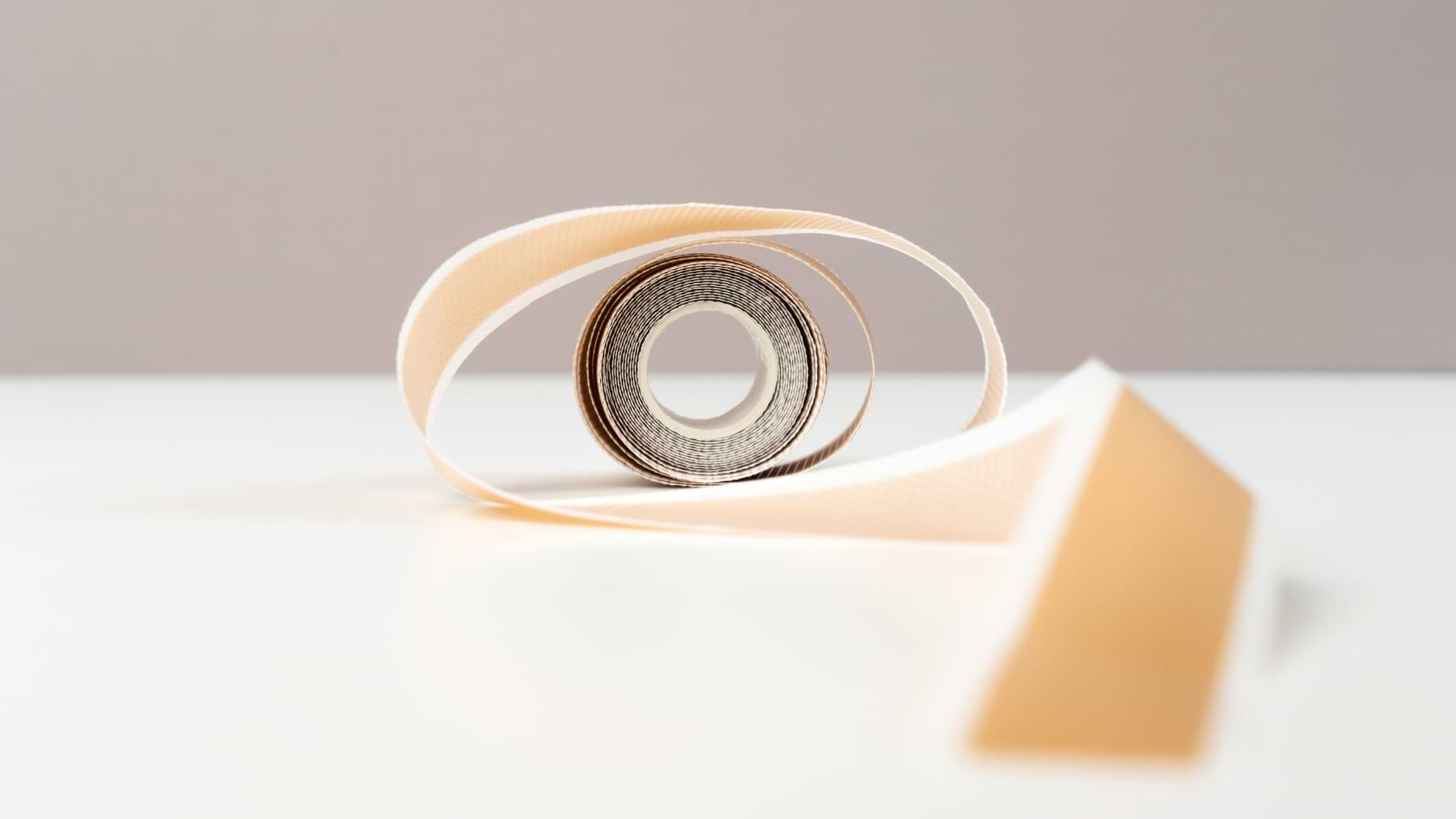 A roll of Nokori Scar Tape partially unfurled, viewed from the front to highlight its spiralled layers.
