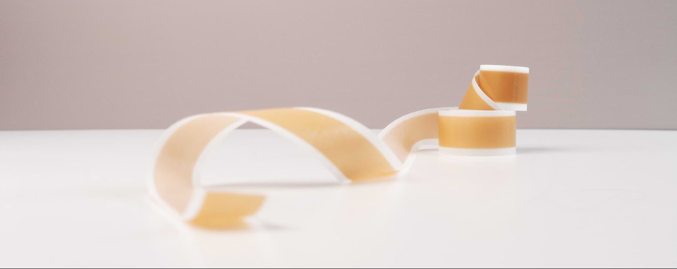 Close-up of a soft silicone scar tape roll resting on a clean surface — minimal and focused on texture.