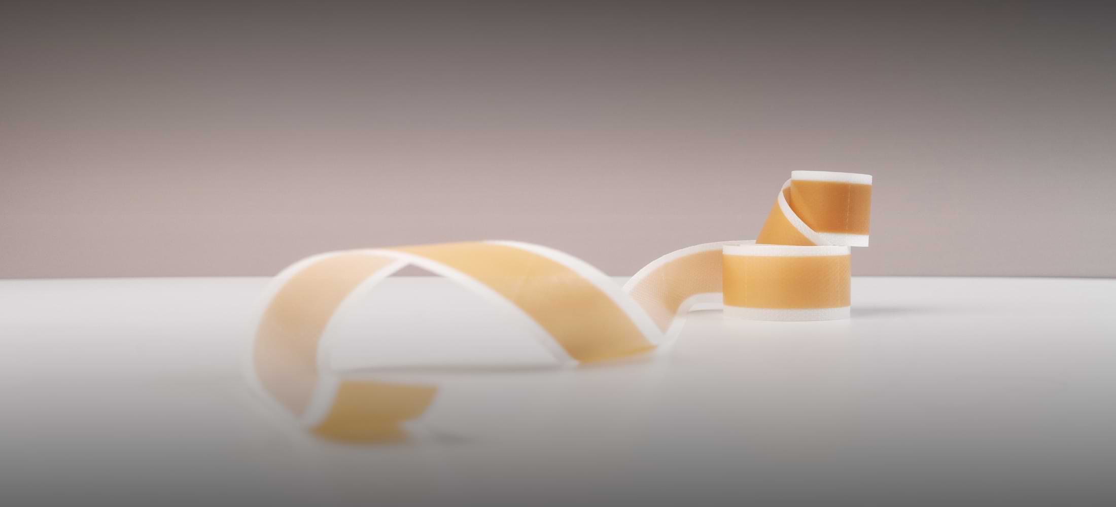 Silicone scar tape roll shown on a neutral background with soft lighting — evoking clinical precision and gentleness.