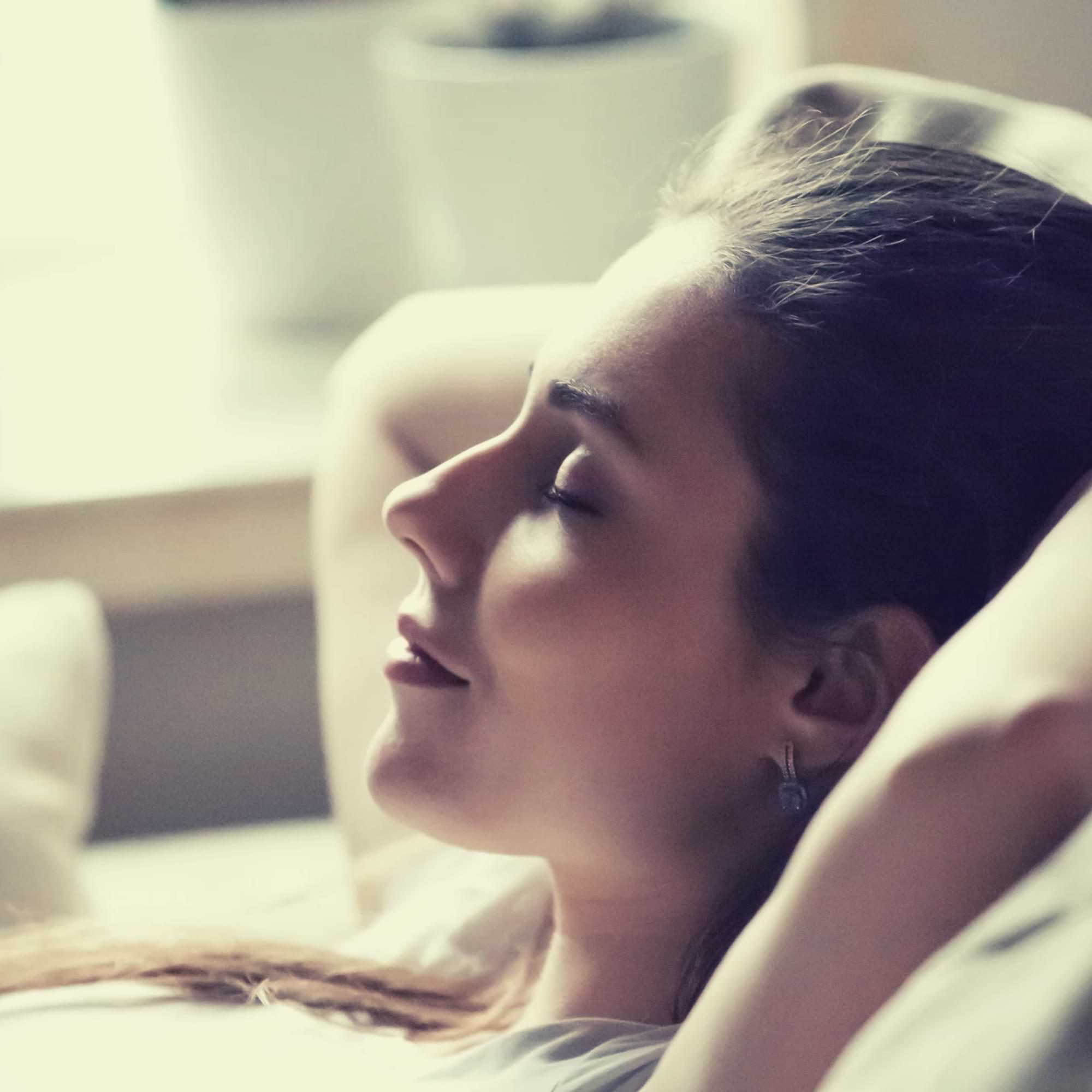 Peaceful moment of a woman resting with eyes closed—embracing stillness and healing.