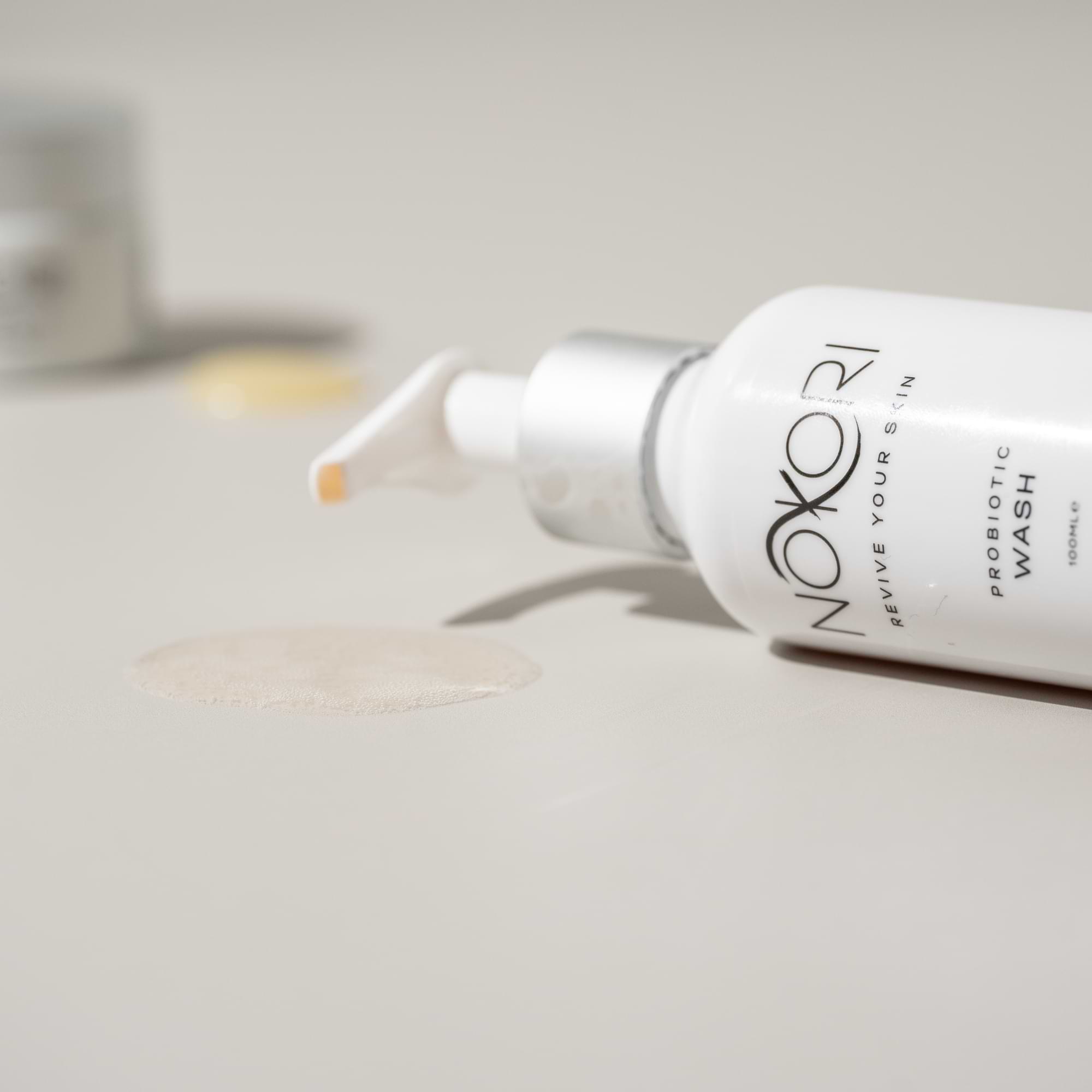 Nokori Probiotic Wash bottle lying on its side with a small puddle of liquid product beside it.