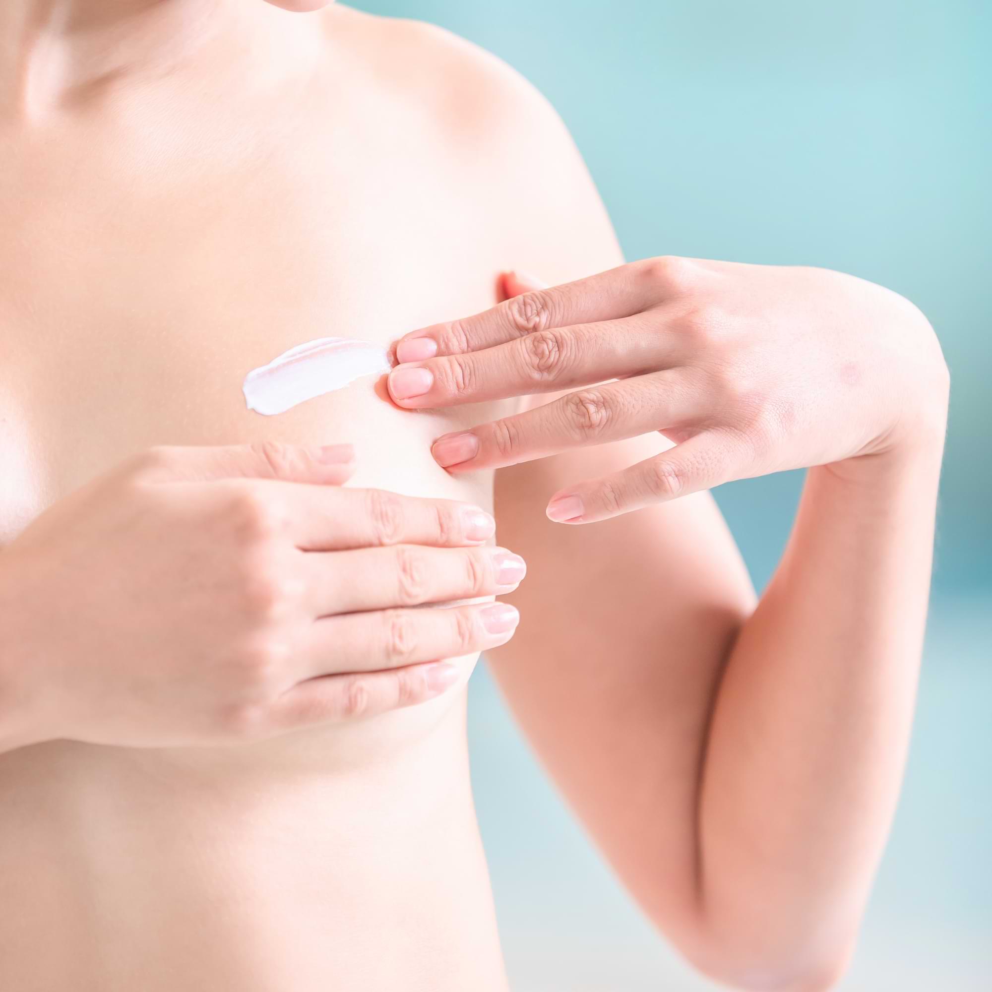 Woman gently applying cream to the chest area—demonstrating mindful scar care.