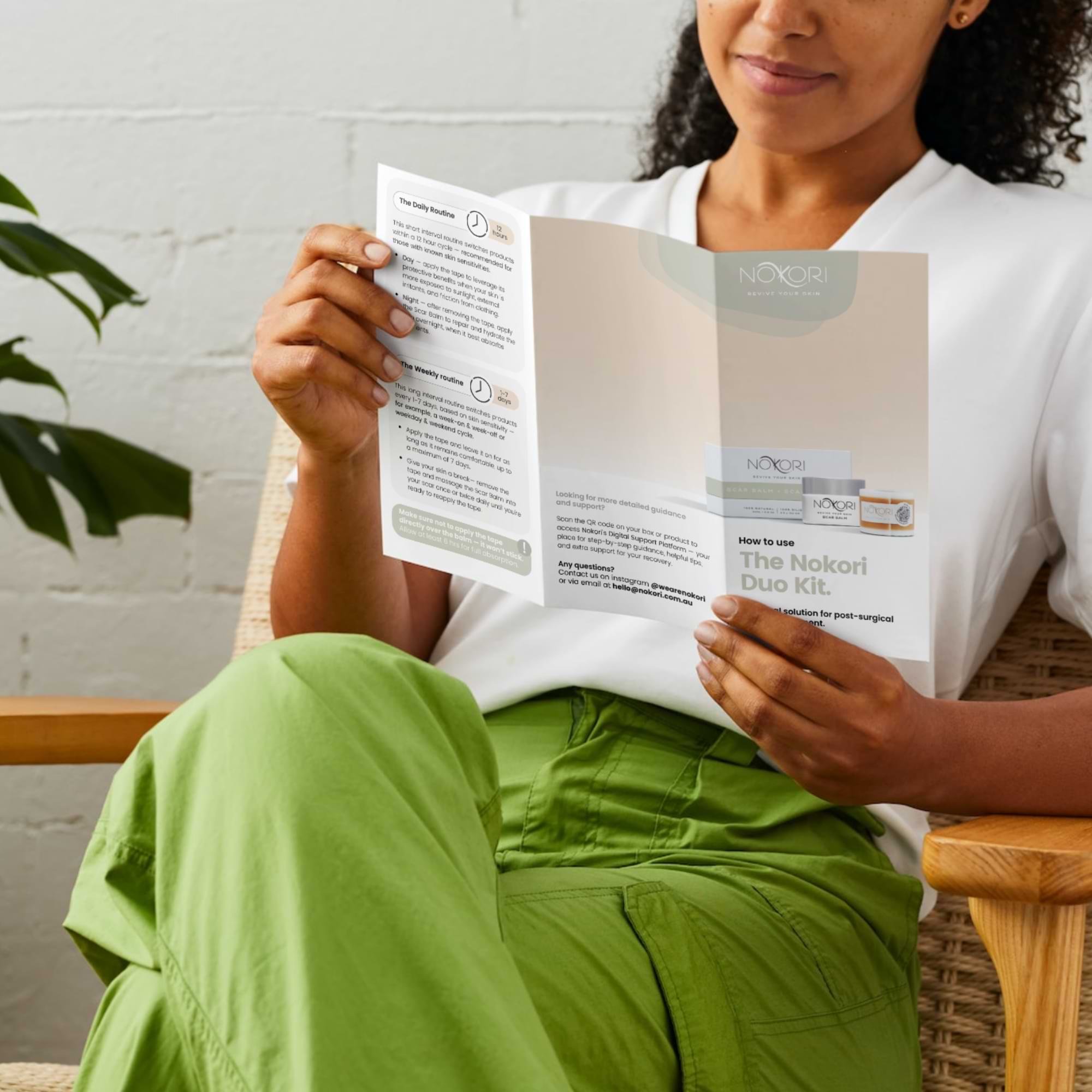 Woman seated, reading a Nokori Duo Kit instruction guide—engaged in her recovery process.