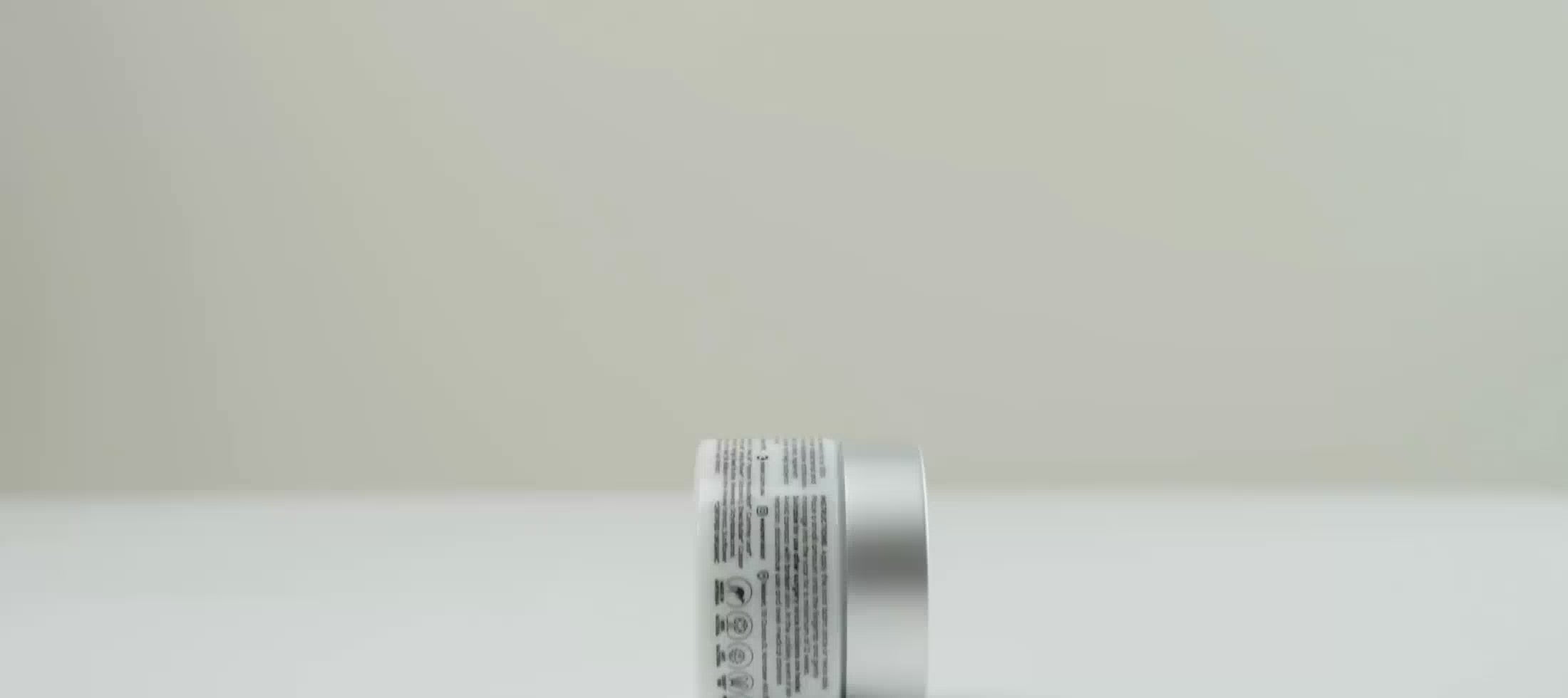 Load video: Nokori Scar Balm jar rolling upright along a flat surface, showcasing the label and design.