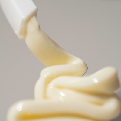 Close-up of Nokori Bio Active Cream being dispensed from a white pump, showing the creamy yellow texture
